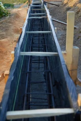 Black plastic sheeting being used to mold concrete foundation