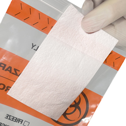 6 x 9 Biohazard White Absorbent Pad Being Slid Into Back Flap on Bag