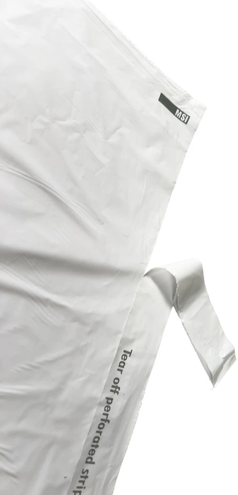Perforated Strip being Removed on Hospitality Plastic Tear Strip Laundry Bags Removing Perforated Strip of 14 x 24 0.8 Mil Plastic Laundry Bags - Eco Friendly