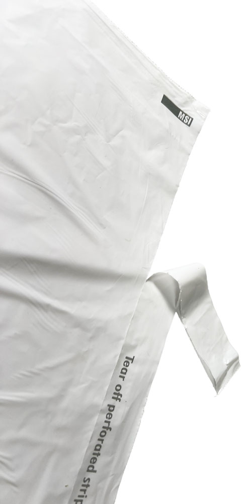 Perforated Strip being Removed on Hospitality Plastic Tear Strip Laundry Bags Removing Perforated Strip of 14 x 24 1.25 Mil Plastic Laundry Bags - Eco Friendly