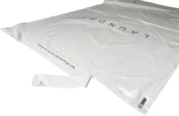 Removing Perfoated Strip on Hospitality Plastic Tear Strip Laundry Bags 14 x 24 0.8 Mil Plastic Laundry Bags - Eco Friendly With Perforated Strip Being Removed