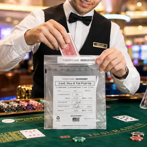 Casino attendant sealing playing cards into a tamper-evident security bag at a table game