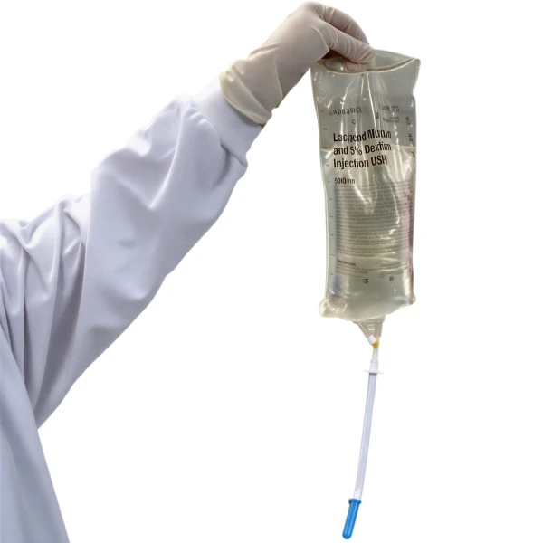 3. Firmly insert the spike into the IV bag outlet, then remove the packaging from the spout. Medical professional holding I±V bag with spike end of decanter inserted